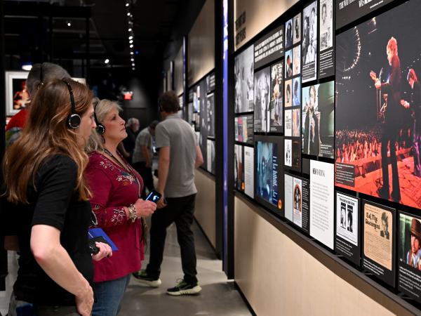 Two women wearing headphones read panels inside the Bob Dylan Center while listening to an audio guide developed by Art Processors.
