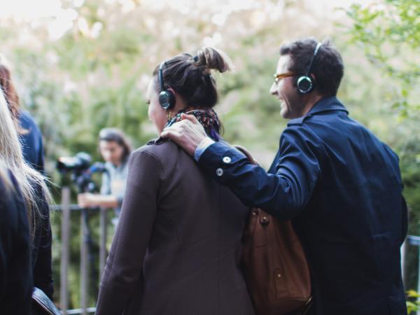 A couple wearing headphones stand together during an I, Animal tour of Melbourne Zoo.