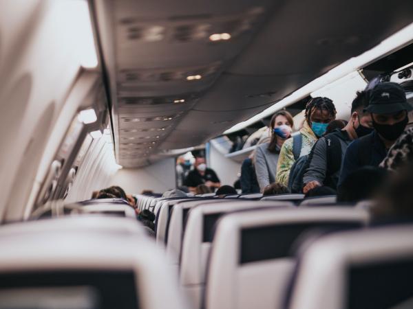 People wearing masks board a plane.