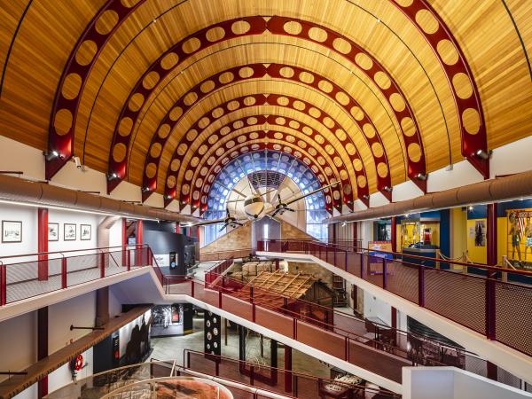 Two storey interior of the Australian Stockman's Hall of Fame showing exhibition installations with walking paths between ground and first floor. An airplane hangs from the domed ceiling.
