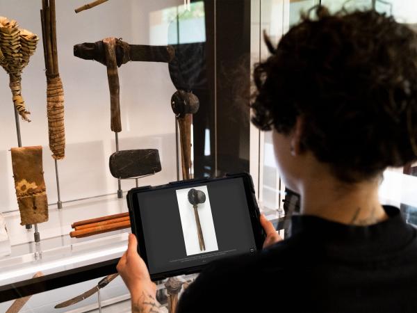 Elliotte holding iPad in front a collection of aboriginal artifacts.