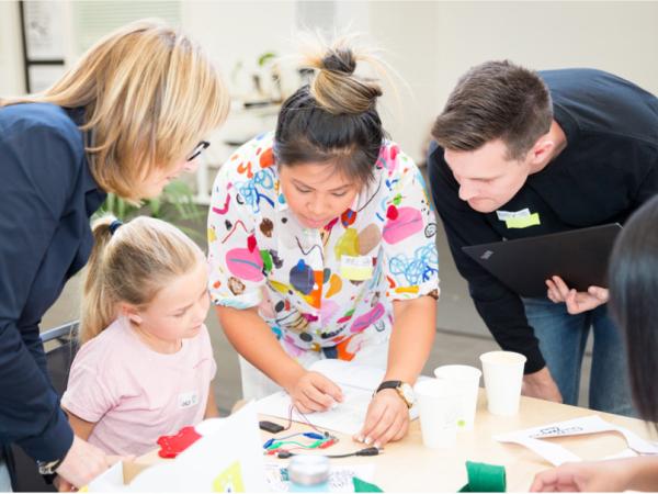 Two DIY Monster volunteers helping a participant and parent/guardian troubleshoot some issues.