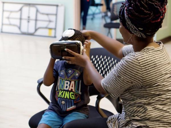 Little boy getting assisted with putting on a VR headset