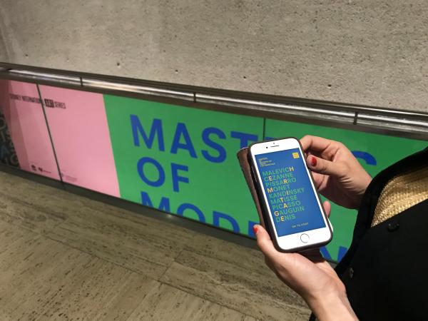 Woman holding mobile device with Masters of Modern Hermitage app open