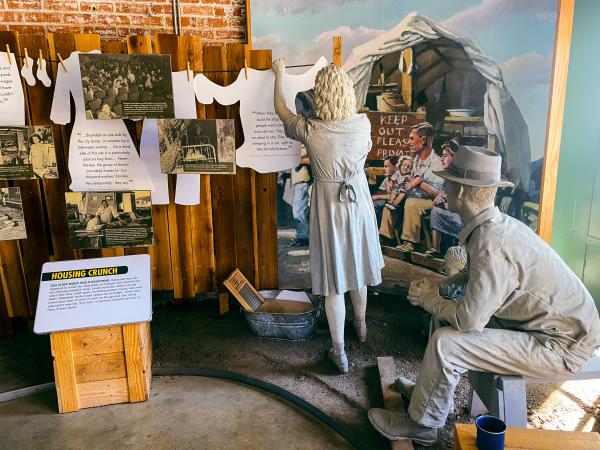Display at the Rosie the Riveter exhibition for the National Park Service. Two mannequins dressed in 1940s clothing accompany photos and information about life during World War II