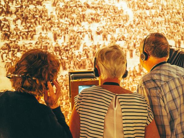 Three people wearing headphones listening to the Spirit of the ANZAC audio experience