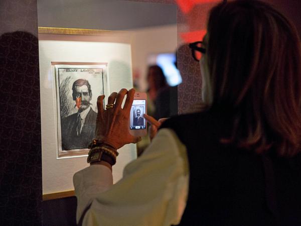 Woman scanning wall art with mobile device at Curio exhibition at the State Library of  SW