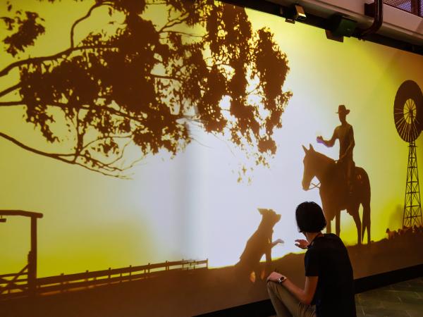 A man interacts with a digital kelpie dog that's part of the Welcome Station at the Australian Stockman's Hall of Fame.