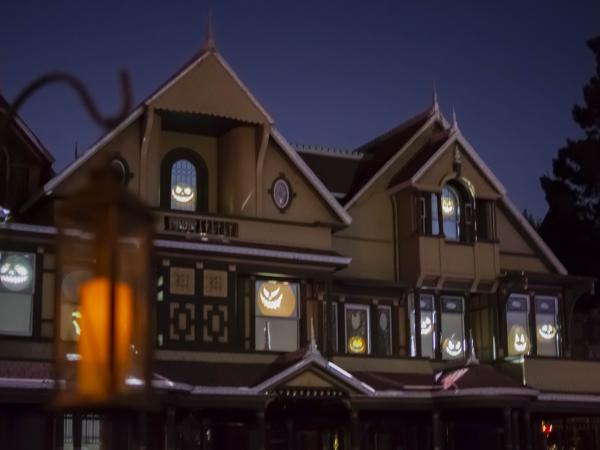 The external buildings of Winchester Mystery House with Halloween decorations and pumpkin faces in the windows.