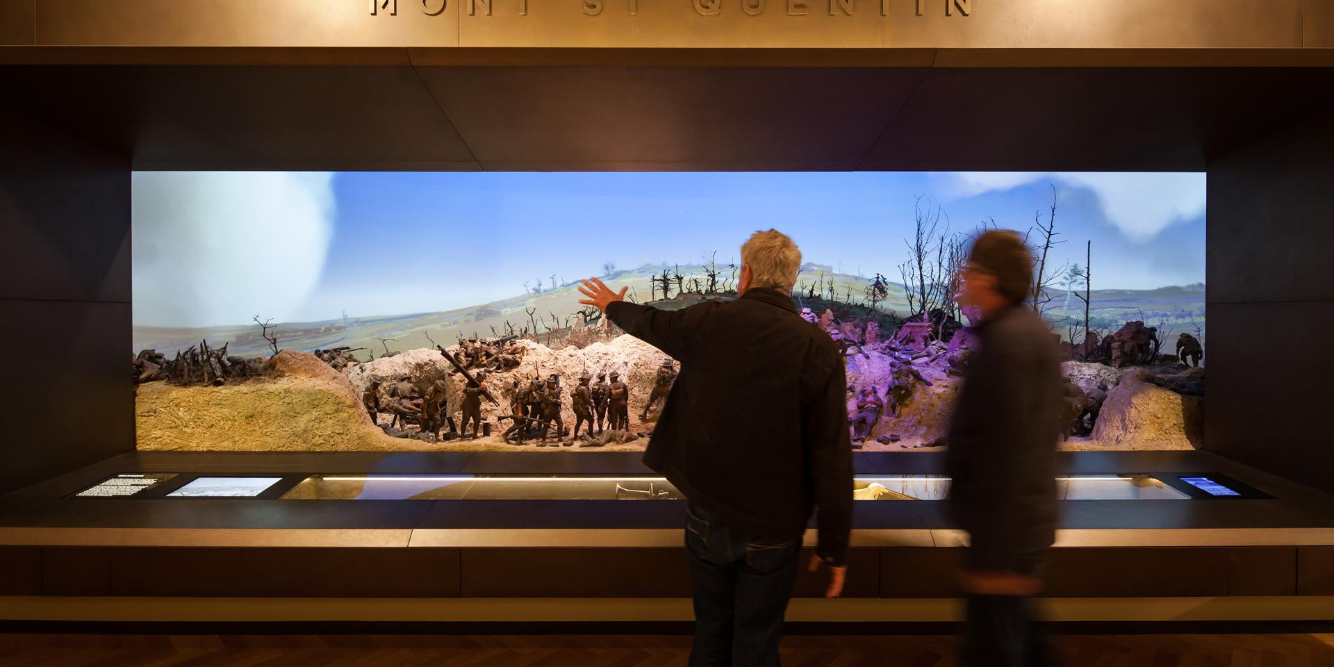 Visitors gesturing in front of diorama at the Australian War Memorial
