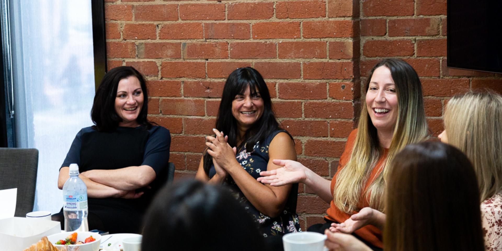 Women sitting around a table laden with food, eating and talking