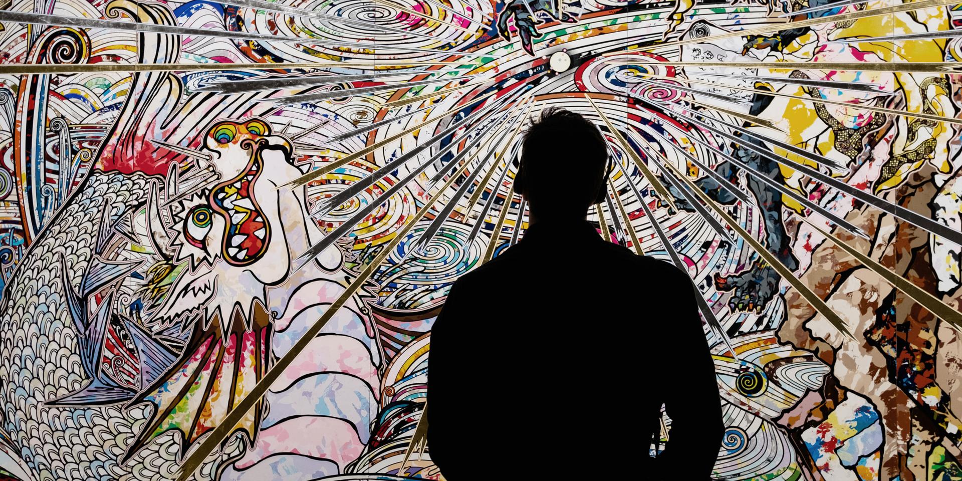 Silhouette of a man with headphones listening to Japan Supernatural audio guide at the Art Gallery of NSW. Large mural artwork is in the background.