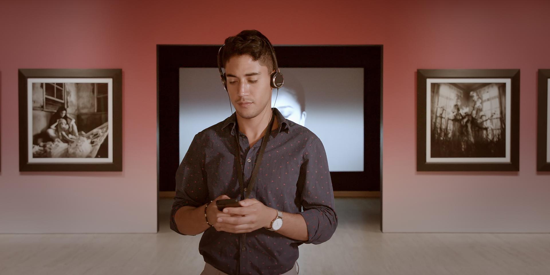 A man wearing headphones listening to the Japan Supernatural audio guide at Art Gallery of New South Wales. 