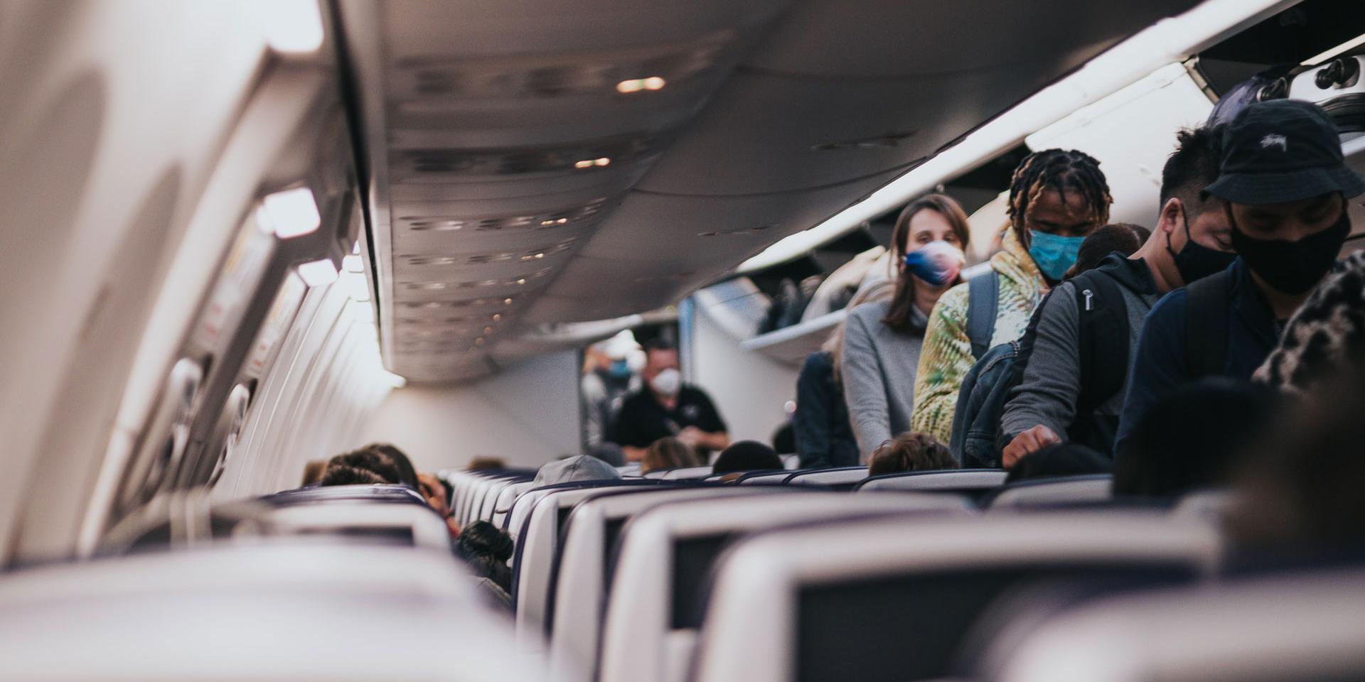 People wearing masks board a plane.
