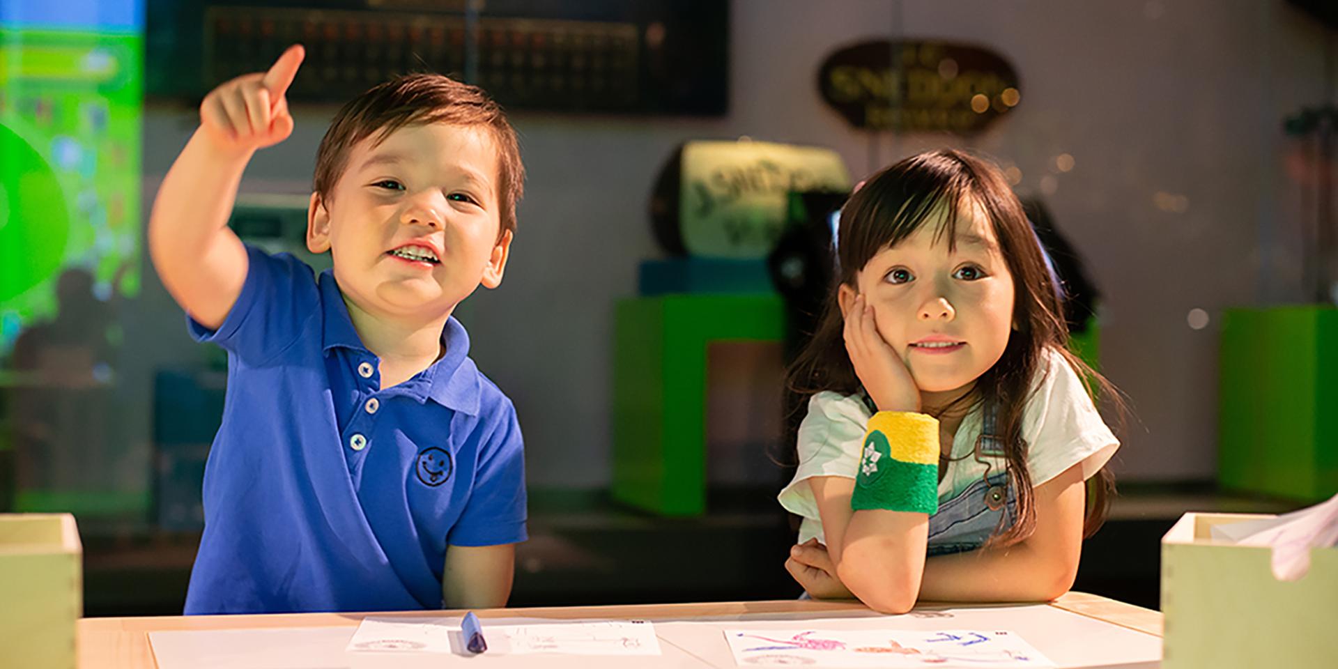Two children sit at a table at the Australian Sports Museum. They are wearing NFC-enabled sweatbands as part of the museum experience.