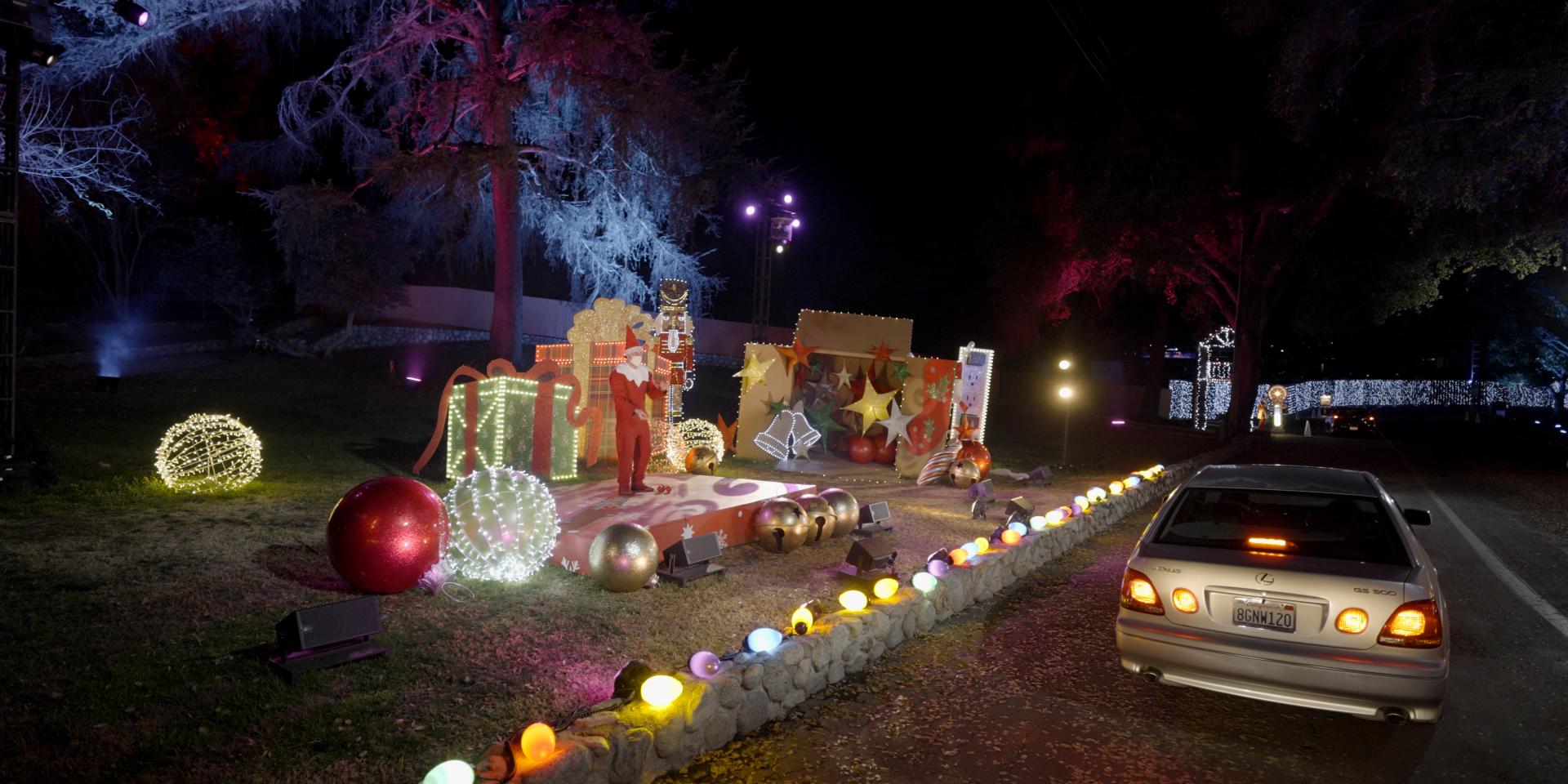 A car driving through the Elf on the Shelf Magical Holiday Journey experience. On the side of the road is are oversized Christmas decorations