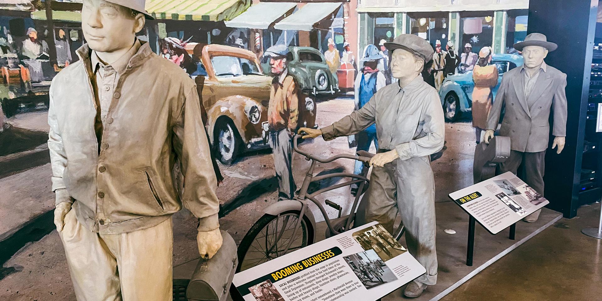 Display at the Rosie the Riveter exhibition for the National Park Service. Mannequins dressed in 1940s clothing stand in front of a 1940s streetscape