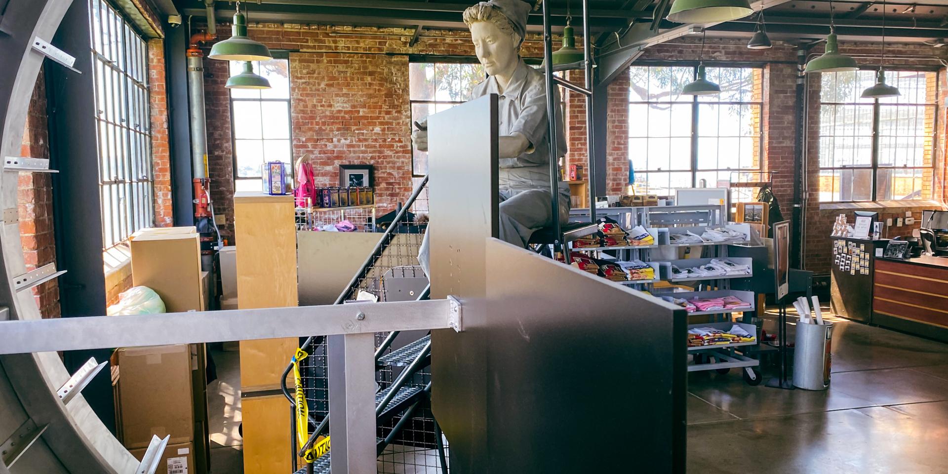 Mannequin dressed as Rosie the Riveter sits at factory installation at the Rosie the Riveter exhibition at the National Park Service. The exhibition gift shop can be seen in the background