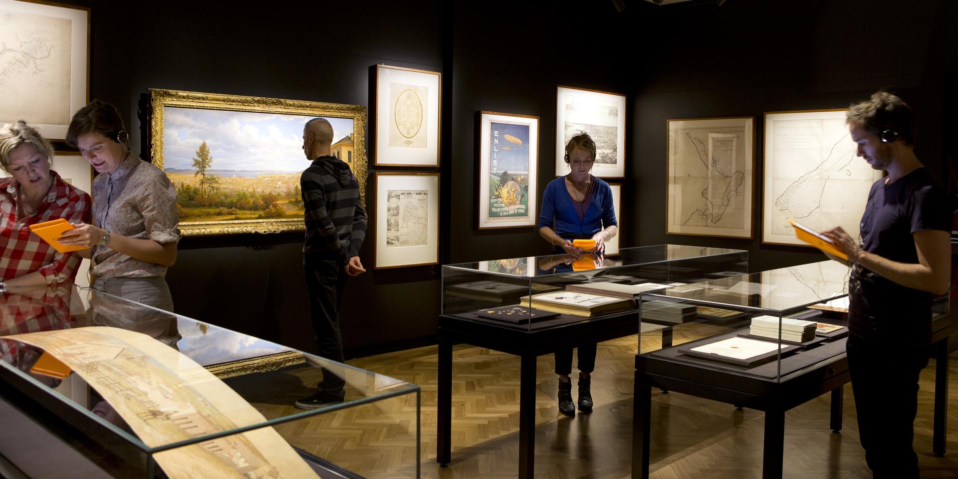 Group of people looking at display cases and wall art at the State Library of NSW Curio exhibition