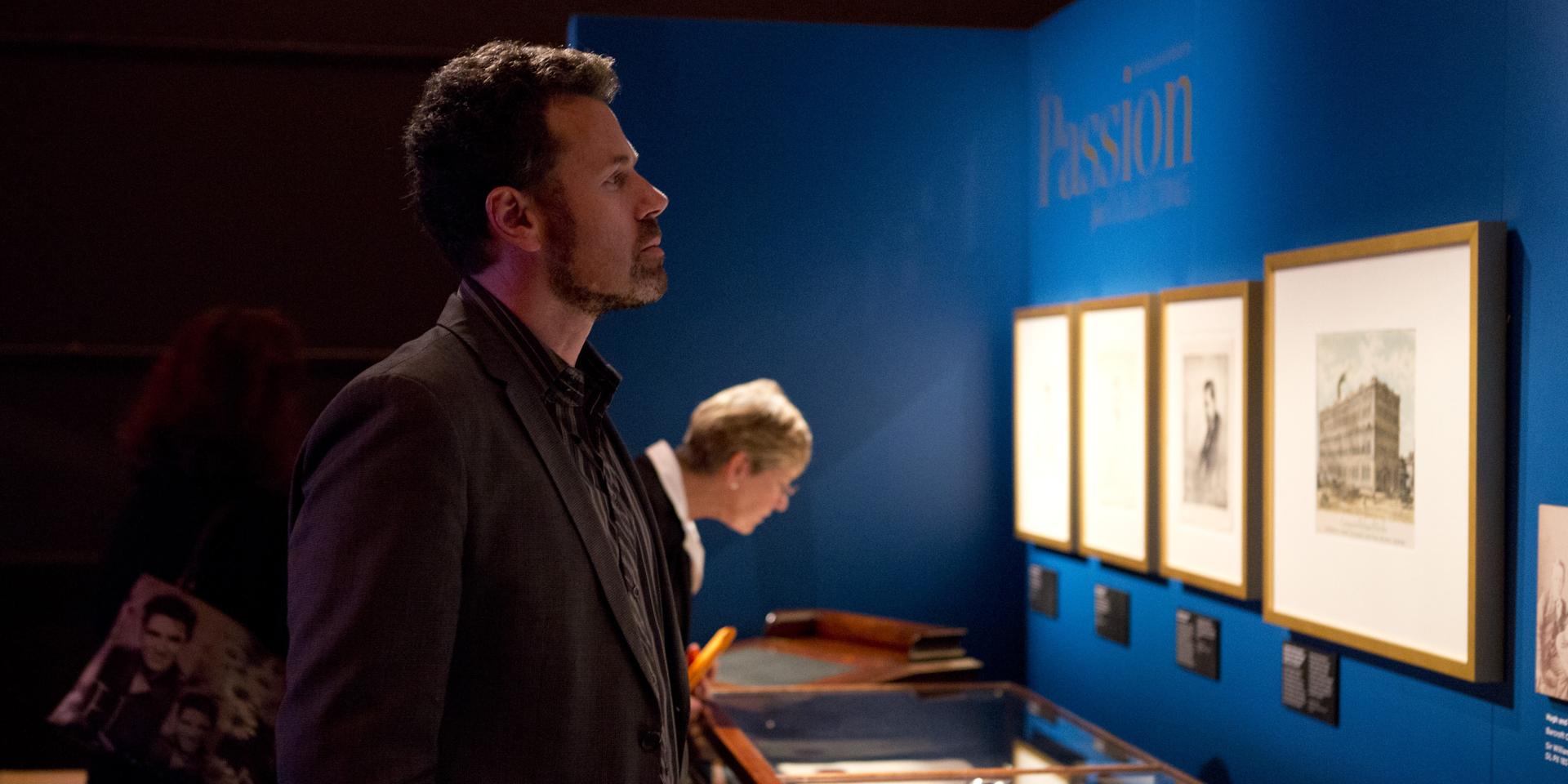 Group of people looking at display cases and wall art at the State Library of NSW Curio exhibition