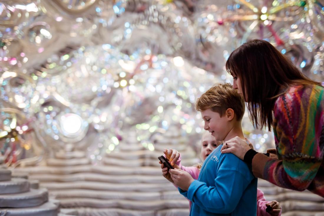 A mother and two young children looking at a mobile device inside the Museum of Old and New Art