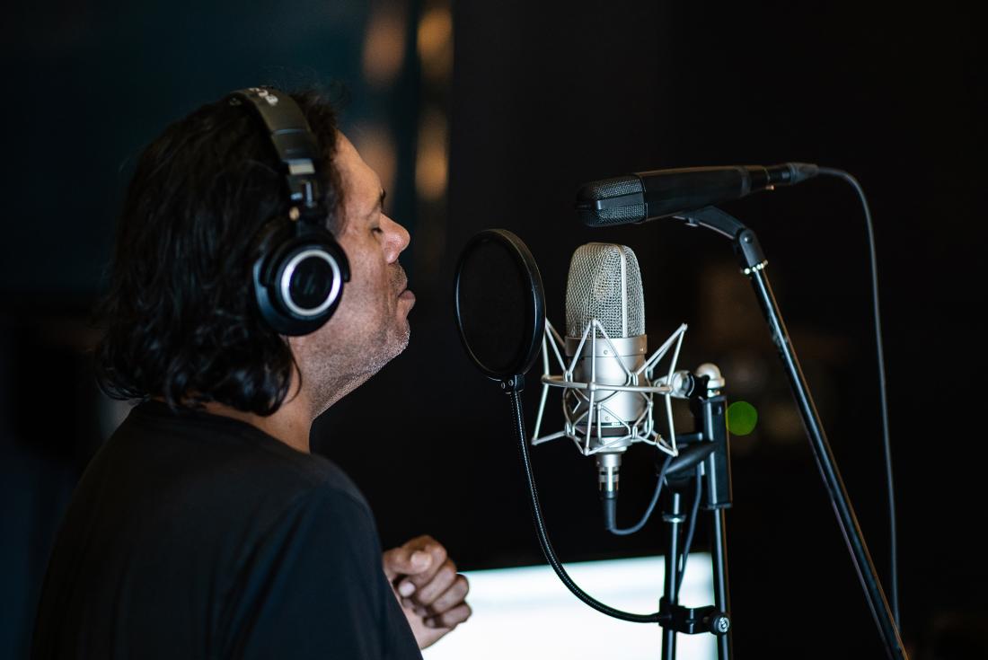 Indigenous Australian musician William Barton sings into a microphone at a recording studio