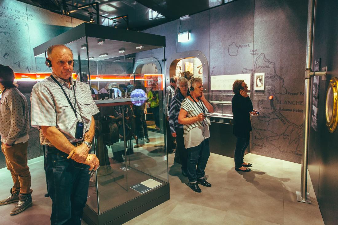 A group of people at the Spirit of the ANZAC touring exhibition. They are all wearing headphones listening to the location aware audio guide