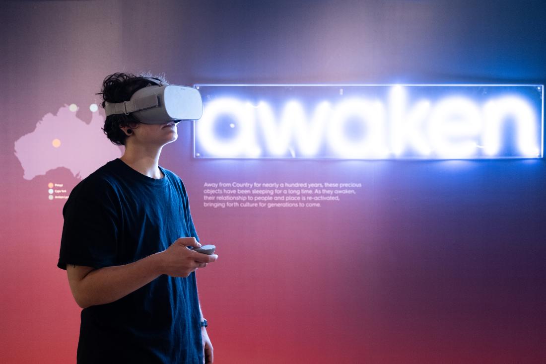 A woman is wearing a VR headset at the Awaken exhibition